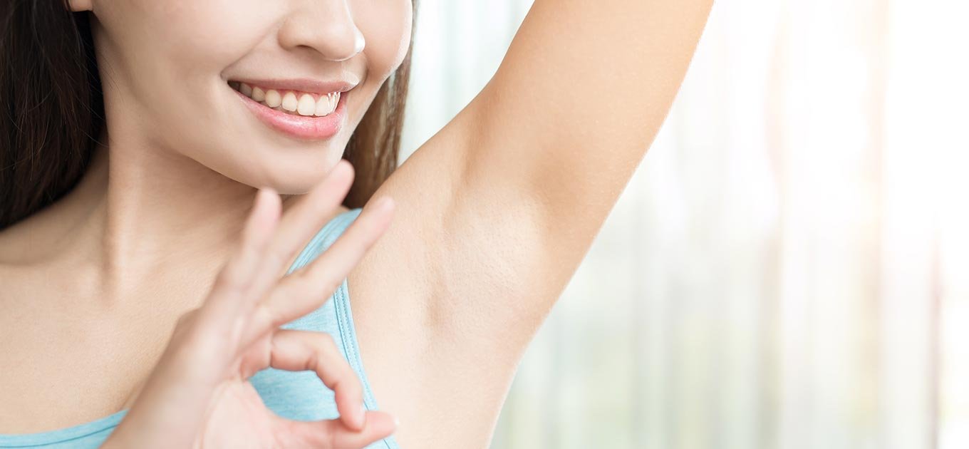 Uśmiechnięta kobieta po zastosowaniu antyperspirantu dla kobiet
