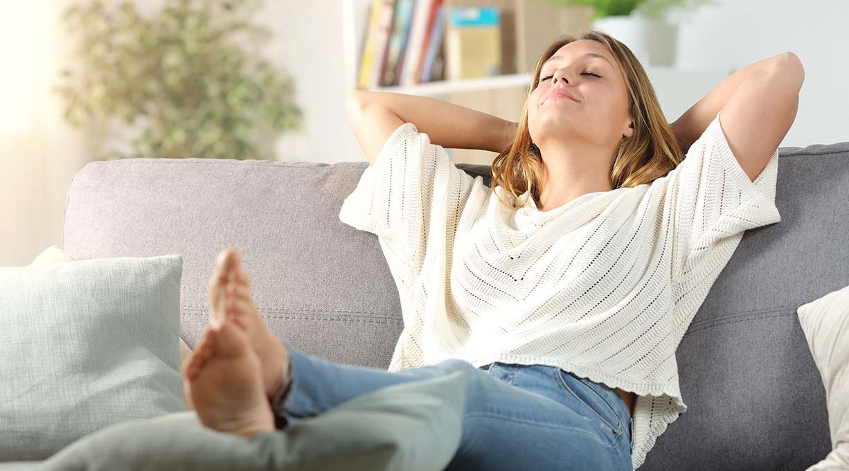 Kobieta czująca się świeżo po zaaplikowaniu antyperspirantu w kulce, relaksuje się na kanapie w salonie