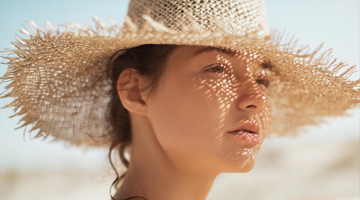 Kobieta na plaży w słoneczny dzień, z kapeluszem na głowie