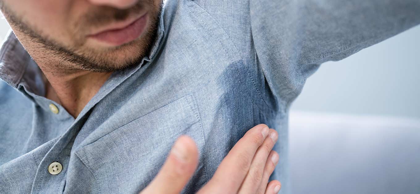 Mężczyzna zastanawiający się, jak sprać plamy z potu