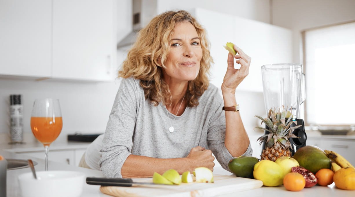 Zdrowa dieta w menopauzie – dojrzała kobieta z owocami w kuchni