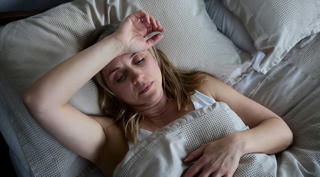Kobieta w okresie menopauzy zmagająca się nadmiernym poceniem w nocy