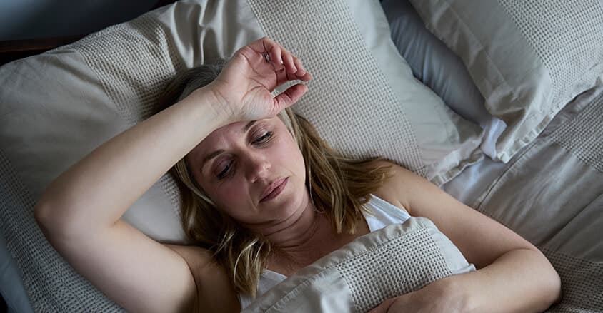 Kobieta w okresie menopauzy zmagająca się nadmiernym poceniem w nocy