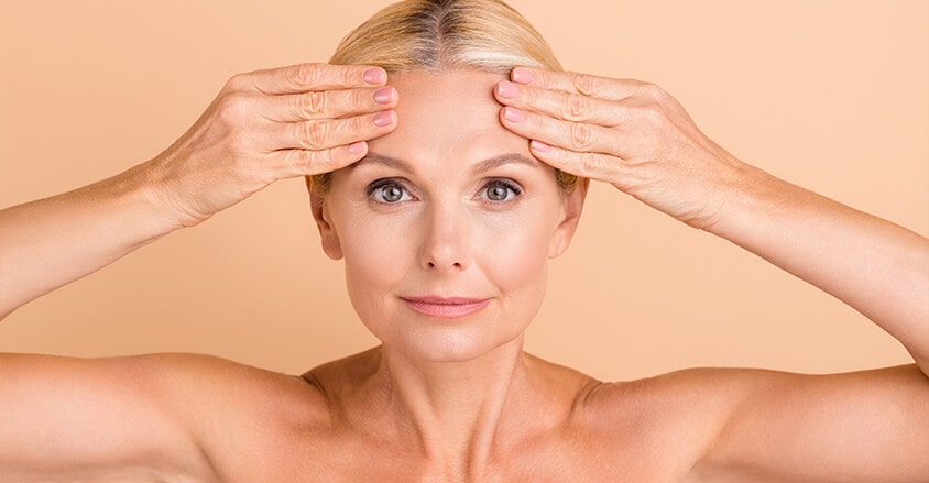Dojrzała kobieta wykonująca masaż czoła na zmarszczki