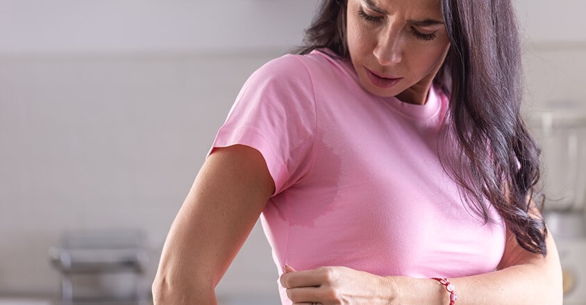 Zmartwiona kobieta zastanawiająca się, jak usunąć plamy z potu