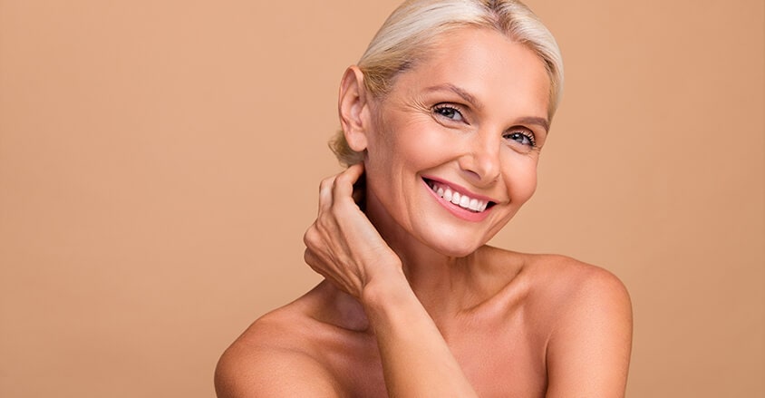 Dojrzała, uśmiechnięta kobieta ze zmarszczkami mimicznymi wokół oczu