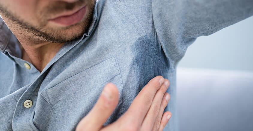 Mężczyzna zastanawiający się, jak sprać plamy z potu