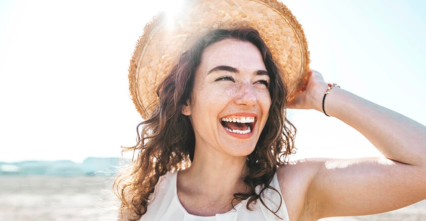 Kobieta czująca się świeżo na spacerze na plaży po zaaplikowaniu antyperspirantu