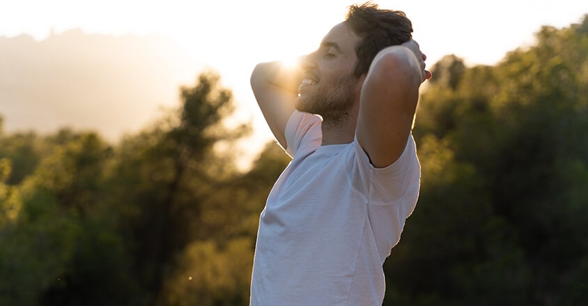 Młody mężczyzna rozciągający się po treningu, bez plam potu, bo ma antyperspirant